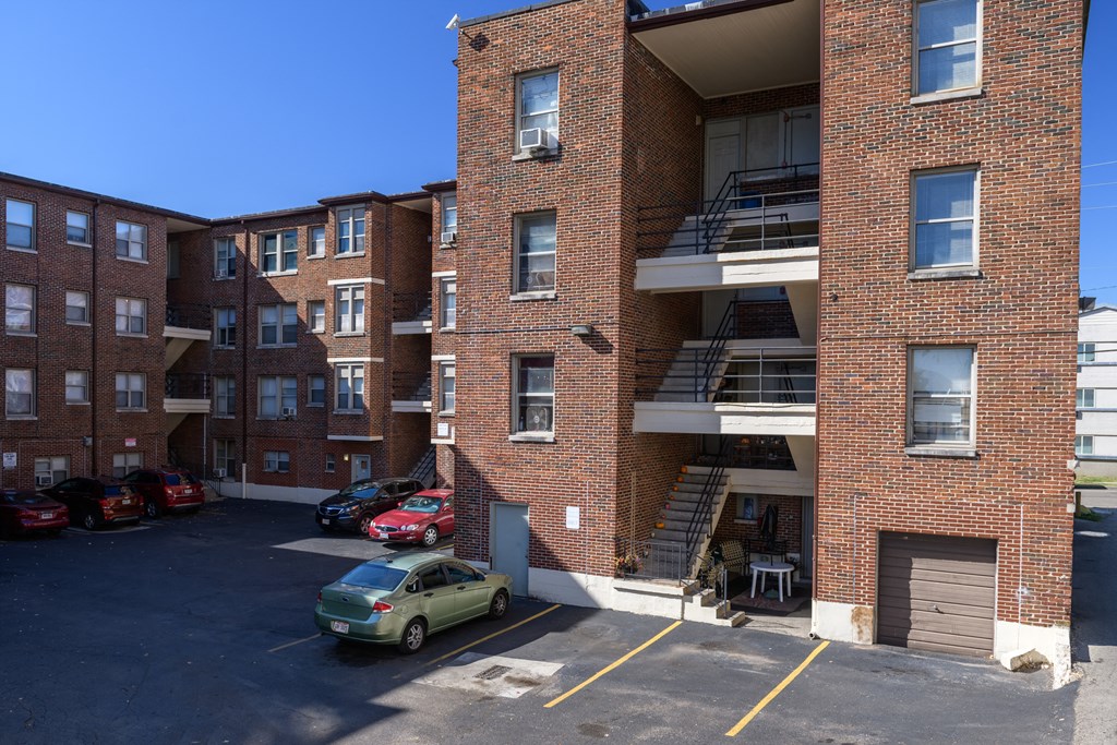 a red brick apartment building with stairs and a parking lot