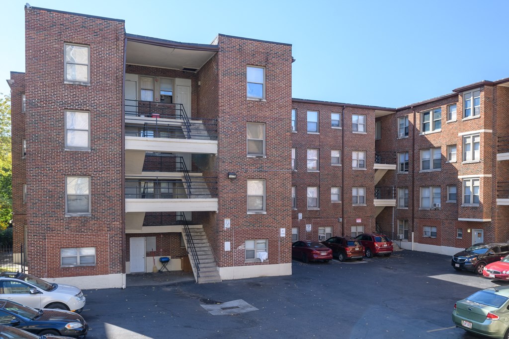 a red brick apartment building with cars parked in a parking lot