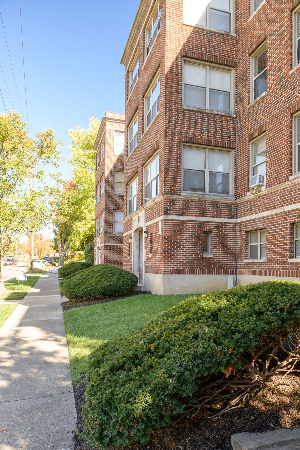 a brick apartment building with a sidewalk in front of it