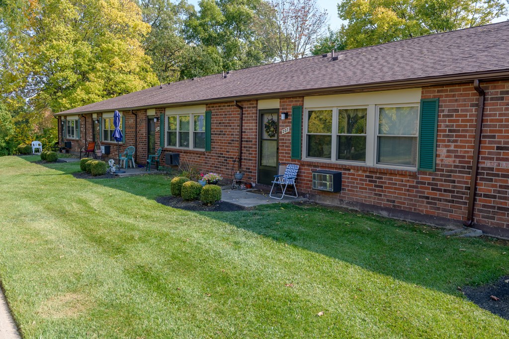 a brick house with green shutters and a lawn