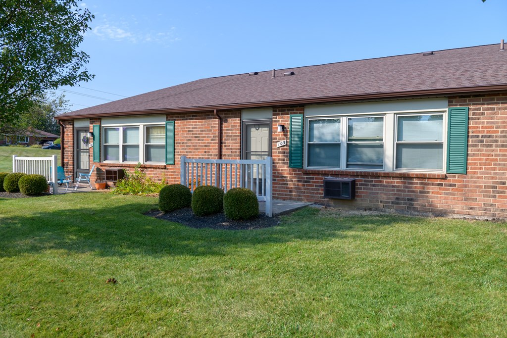 a brick house with green shutters and a lawn