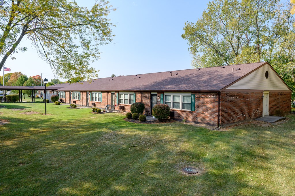 the front of a brick house with grass and trees