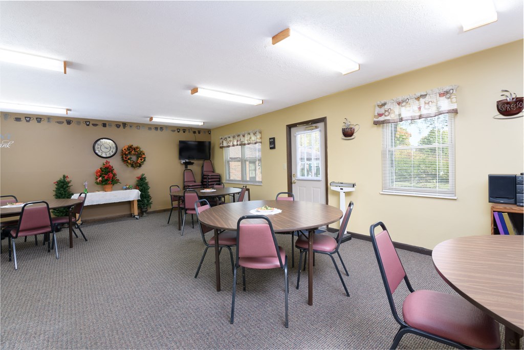 a community room with tables and chairs and a television