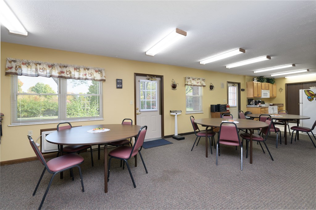a dining room with tables and chairs and a kitchen