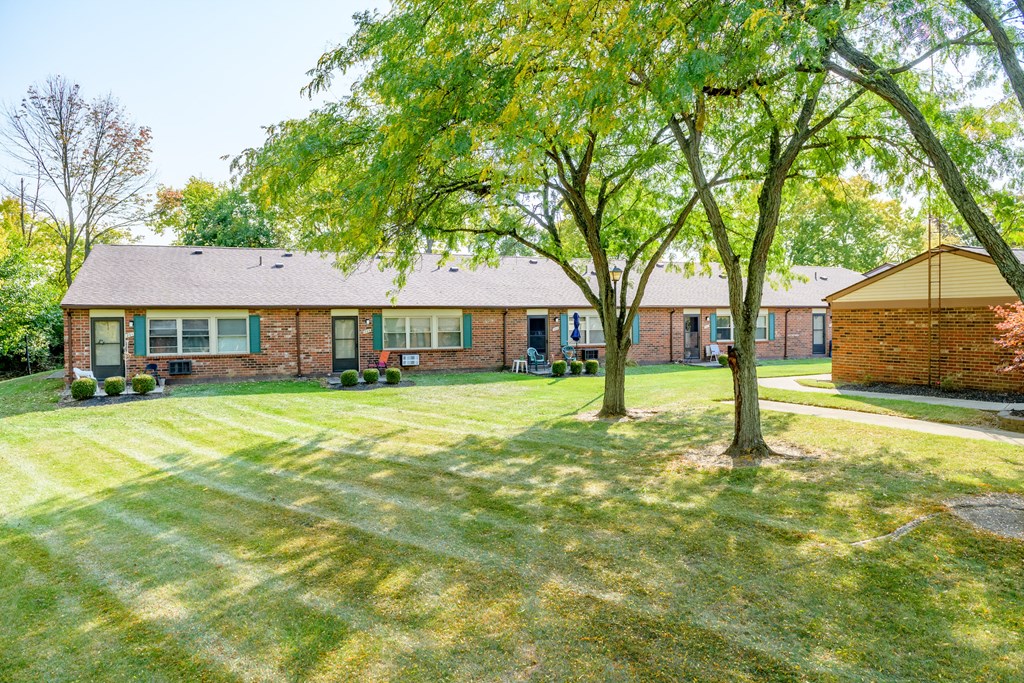the front of a brick house with a yard and trees