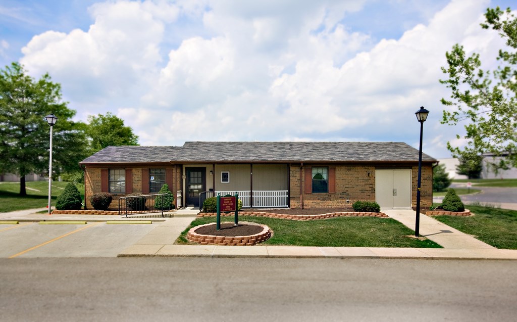 a small brick house with a yard and a sign in front