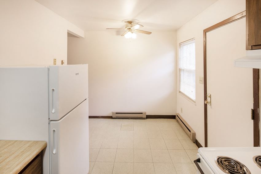 a kitchen with white appliances and a refrigerator and a door to a room