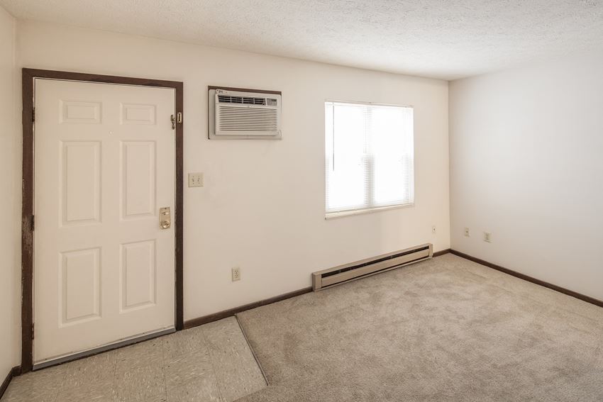 an empty living room with an air conditioner and a white door