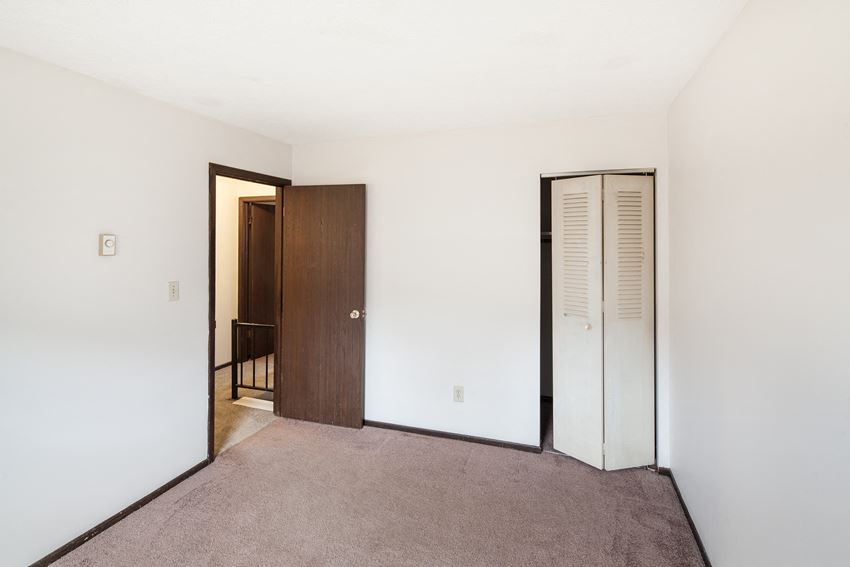 an empty room with a carpeted floor and a door to a closet