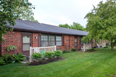 the front of a brick house with a white porch and a lawn