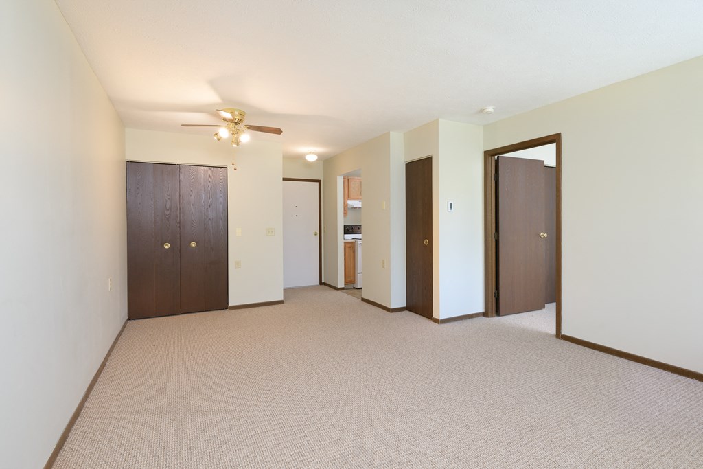 an empty living room with a ceiling fan and a closet