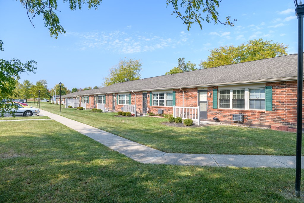 a brick house with green grass and a sidewalk