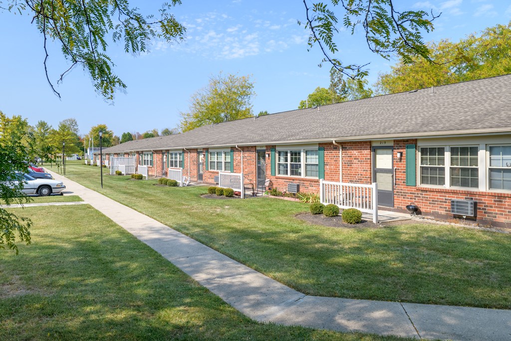 a brick house with green grass and a sidewalk