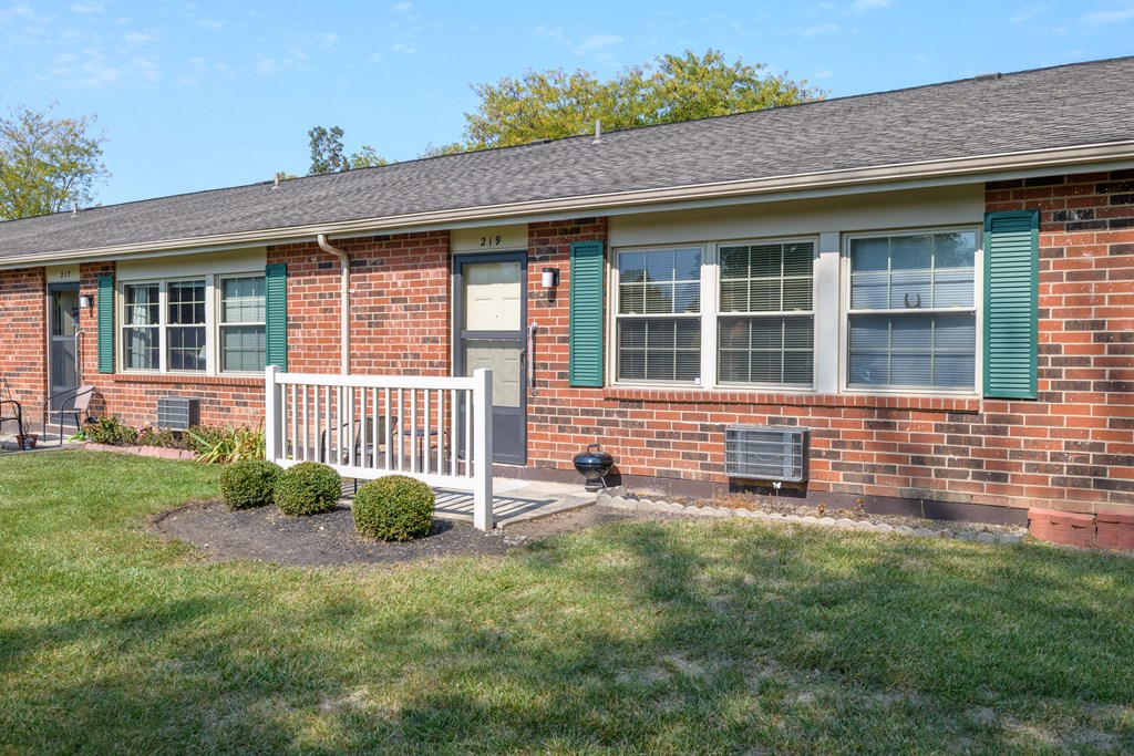a brick house with green shutters and a porch