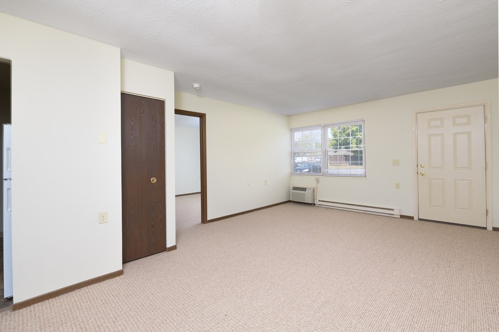 an empty living room with a door and a window