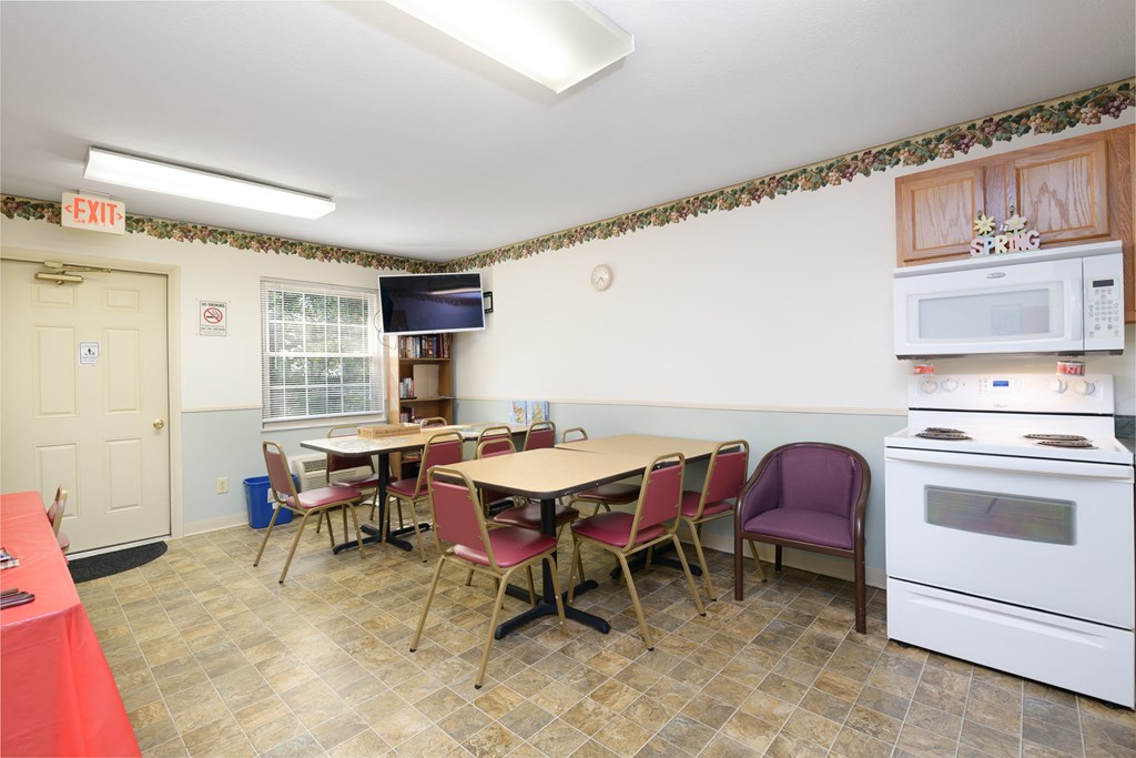 a dining room with a table and chairs and a kitchen with a stove and microwave