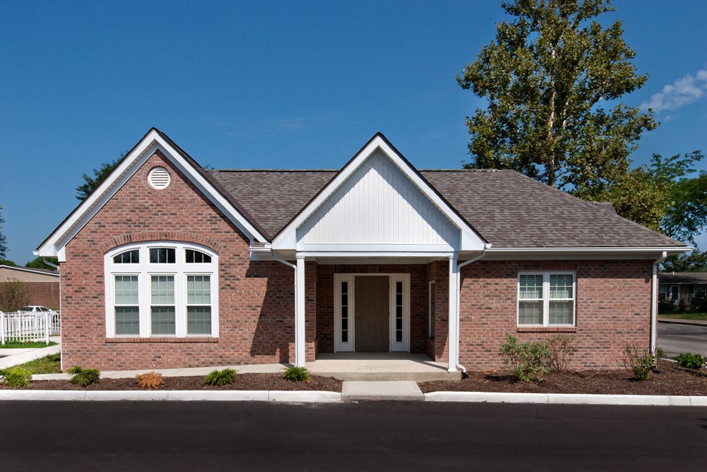 the front of a brick house with a white door and a tree
