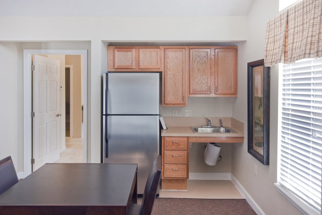 a kitchen with a stainless steel refrigerator and a table and chairs