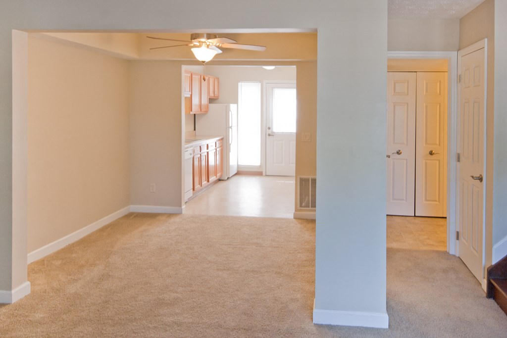 an empty living room and kitchen with a ceiling fan
