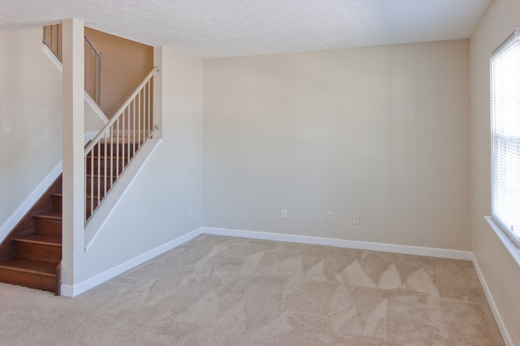 an empty living room with a staircase in a home