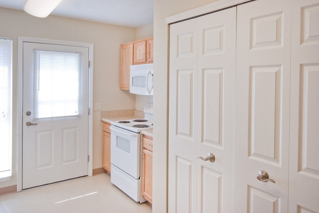 a kitchen with white appliances and wooden cabinets and a white door
