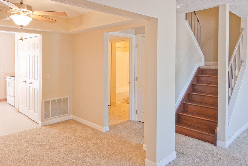 a living room with a staircase and a ceiling fan