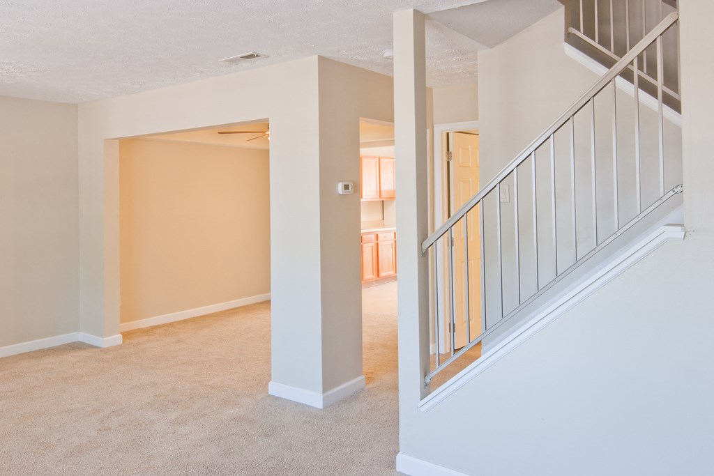 an empty living room with a staircase in a house