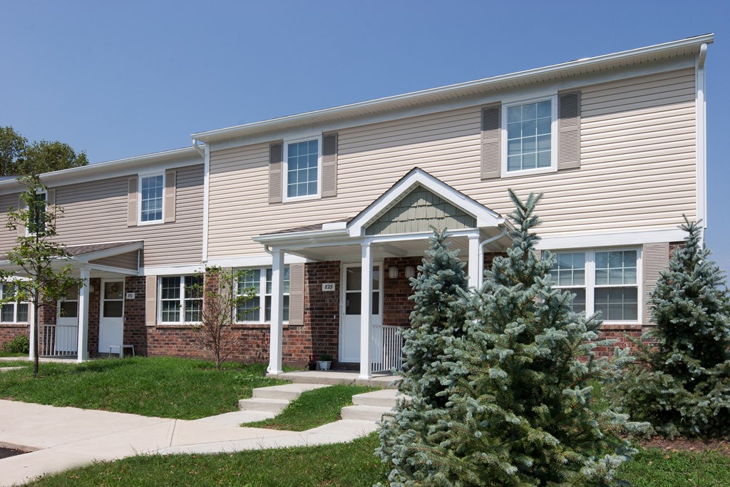 a house with a sidewalk and trees in front of it