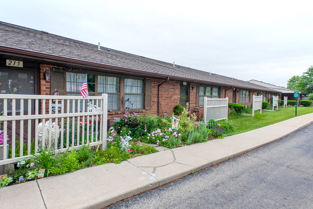 a house with a white fence and flowers in front of it