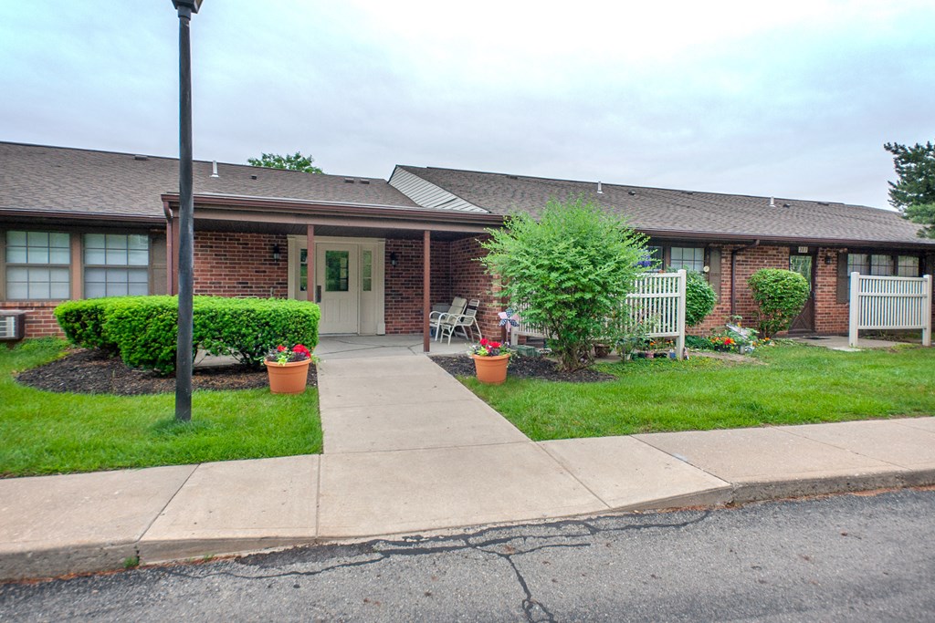 the front of a brick house with a sidewalk and grass