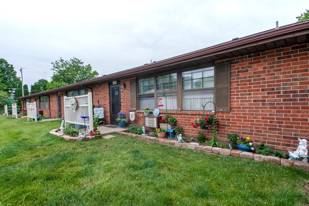 the side of a brick house with a porch and a lawn