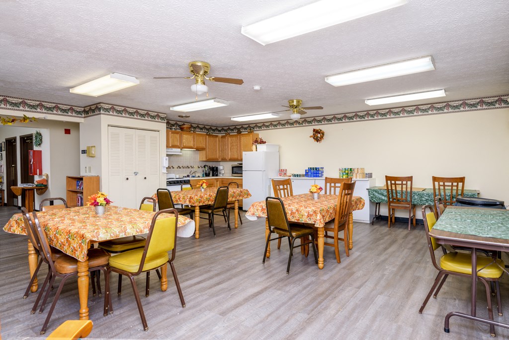 a dining room with tables and chairs and a kitchen