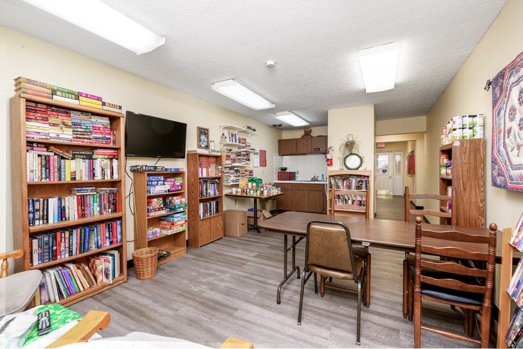 a library with a dining table and chairs and bookshelves
