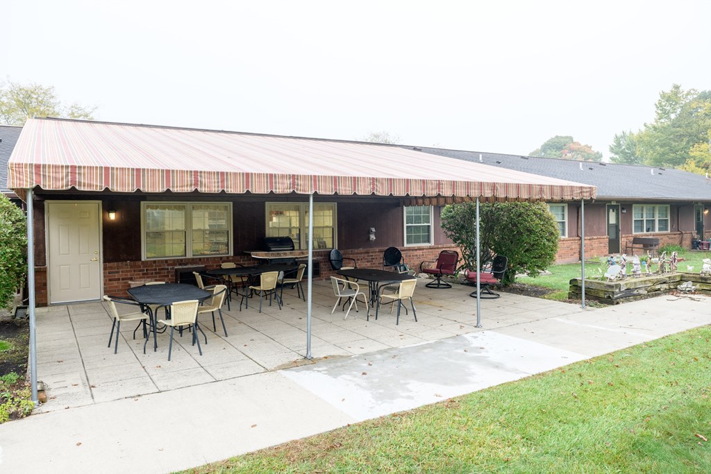 a patio with tables and chairs in front of a house