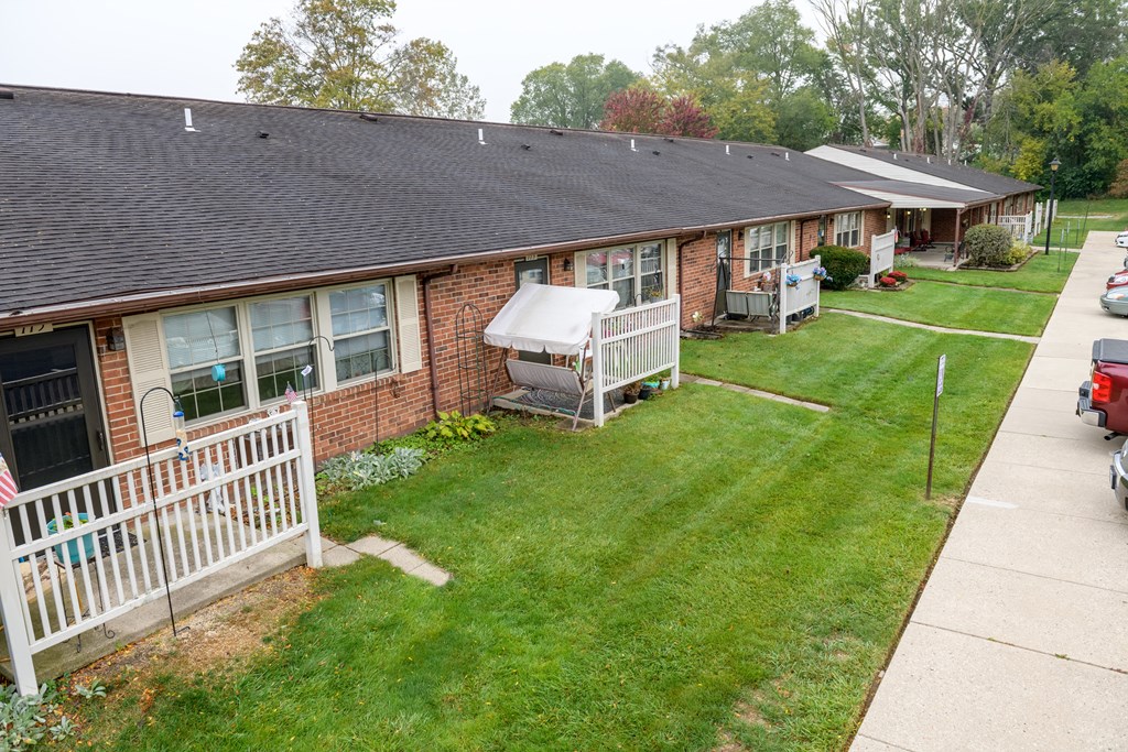 a view of the front of a brick house with a yard and a white fence