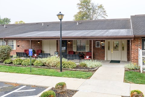 the front of a brick building with a porch and a lawn