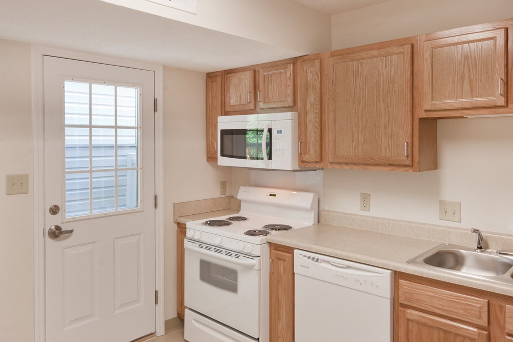 a kitchen with white appliances and wooden cabinets and a white door
