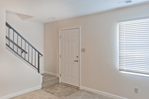the entrance to a home with a white door and a staircase