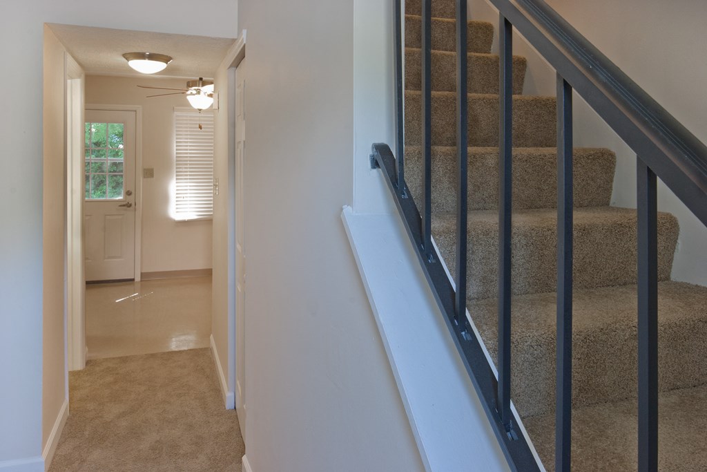 a staircase in a home with carpeted stairs and a hallway with a white door