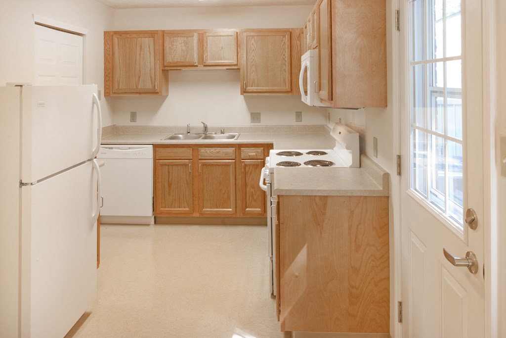 a kitchen with wooden cabinets and white appliances and a window