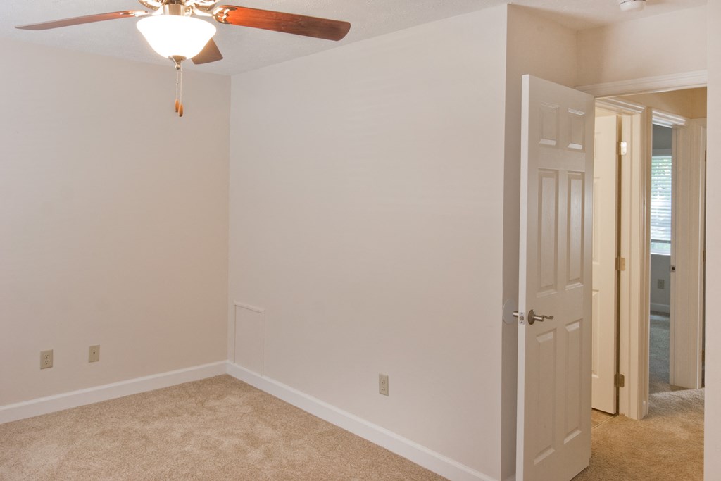 an empty bedroom with a ceiling fan and a door to a closet