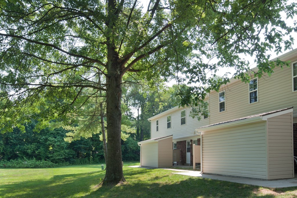 the side of a house with a yard and a tree