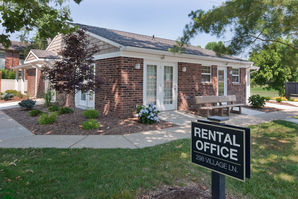 a rental office sign in front of a brick building