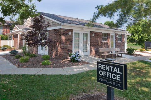 a rental office sign in front of a brick building