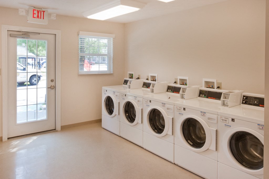 a row of washers and dryers in a laundry room with a door