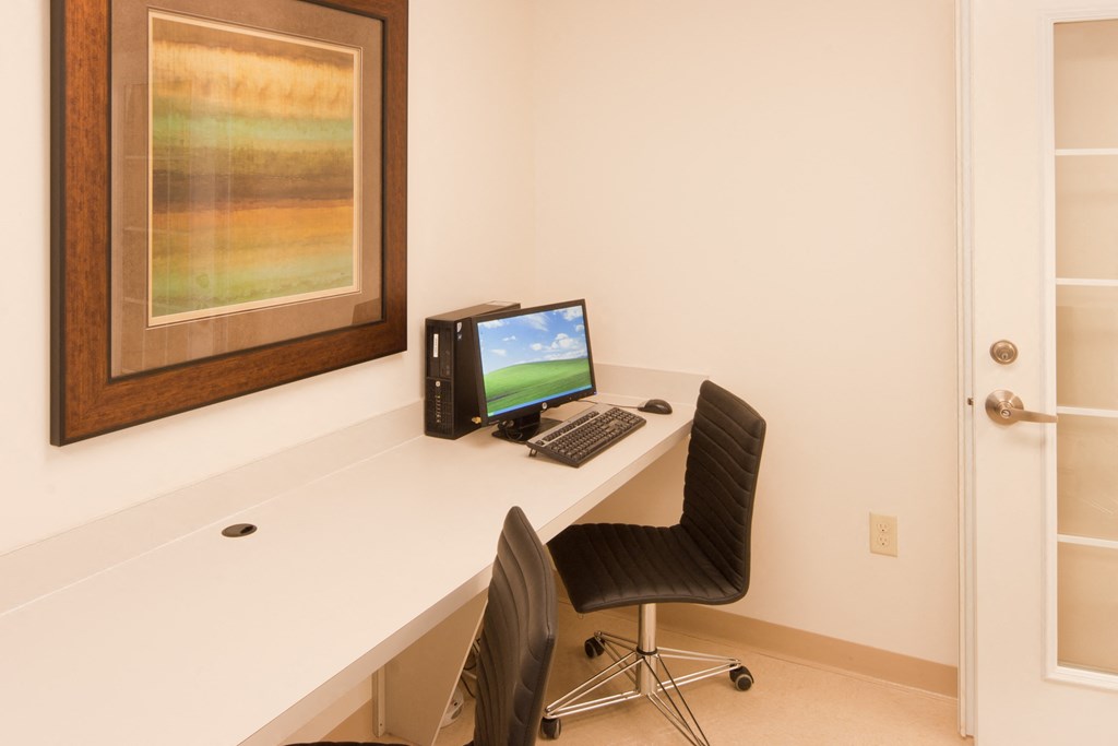 a desk with a computer and a chair in a room