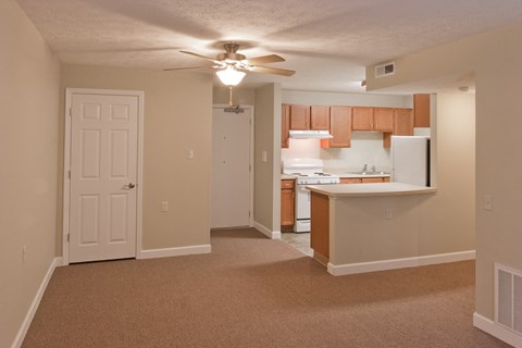 an empty living room and kitchen with a ceiling fan