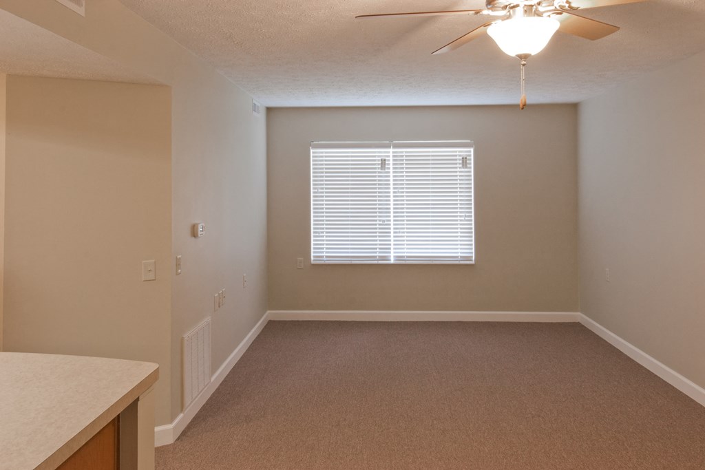 an empty living room with a window and a ceiling fan
