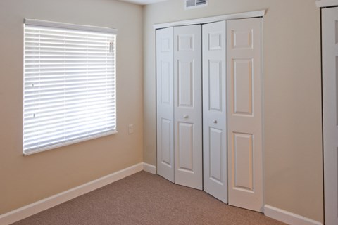 a bedroom with two closets and a window with blinds