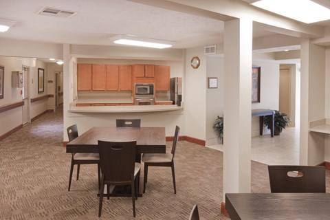 a dining room area with a table and chairs and a kitchen in the background